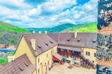 Fototapeta na wymiar Courtyard of medieval Loket Castle (Hrad Loket) gothic style building on massive rock with green forest hills and blue cloudy sky background, Karlovy Vary Region, West Bohemia, Czech Republic