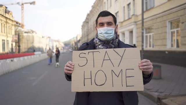  Man in medical mask  stand with poster on city street. Word pandemic team