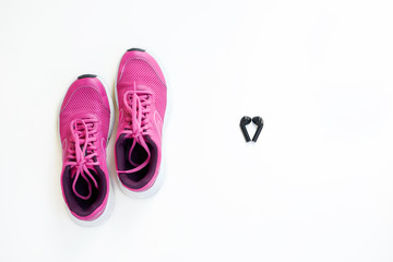 Modern pink running shoes for women and headphones on a white background.