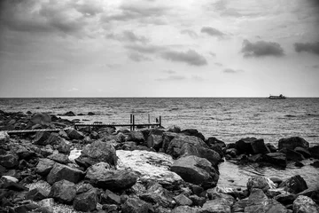 Foto auf Acrylglas Schwarz und weiss Ozeanwellen mit einem Fischboot an einem windigen Tag in Schwarzweiss.