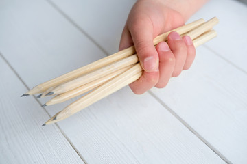 girl's hand holding a bunch of pencils against white background. back to school concept. time to go to school after coronavirus lockdown. 