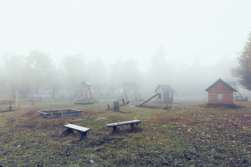 Playground in a small town in the early autumn morning. Heavy fog.