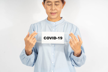 A Middle age asian woman holding a medical face mask, there is Covid-19 card, blank space template. Encourage health care from Covid 19 Corona virus, on white background.