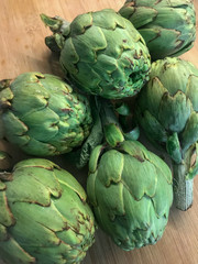 Raw artichokes on wooden table