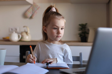 Fototapeta na wymiar Serious little girl handwrite study online using laptop at home, cute happy small child take Internet web lesson or class on PC.