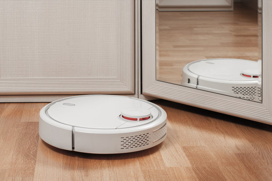 reflection of white robotic vacuum cleaners. modern smart appliance for cleaning house