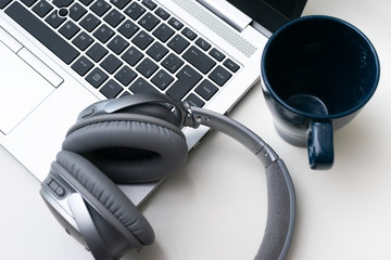 Headphones over an open laptop and a cup on the top right corner. Top right point of view