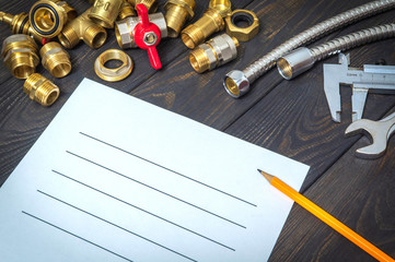 Drawing up a plumbing repair plan with spare parts and hoses on black wooden boards