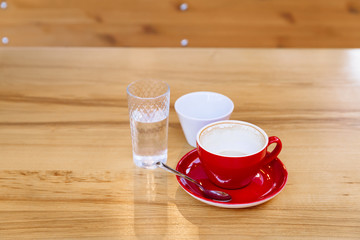 Dirty coffee cups, cappuccino and a glass of water stand on a wooden table.