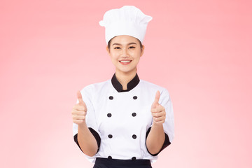 Beautiful Asian chef woman smile and make thumbs up good hand sign  isolated on pink background,Happiness and Cheerful Professional chef Concept