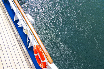 Railing on cruiseship or cruise ship liner with wooden deck and life buoy