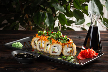 set sushi rolls on a round plate on a dark wooden background