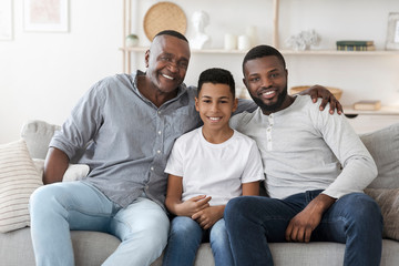 Portrait of smiling millennial black dad, son and grandfather at home