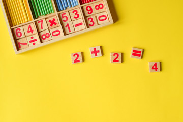 Wood numbers on a yellow background. Primary school, first grade. Mathematics. Two plus two equals four