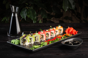 set sushi rolls on a round plate on a dark wooden background