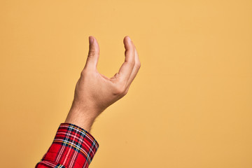 Hand of caucasian young man showing fingers over isolated yellow background picking and taking...