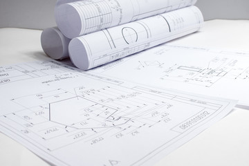 engineering drawings and rolls of drawings are on a white table