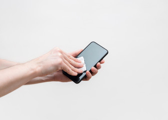 Mobile phone disinfection on a white background. Men's hands cleans the phone with a sanitizer. Prevention of coronavirus, covid-19.