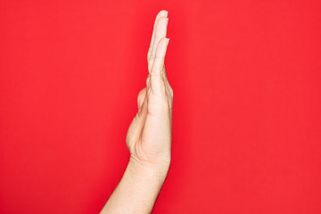Hand of caucasian young man showing fingers over isolated red background showing side of stretched hand, pushing and doing stop gesture