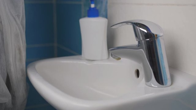 The woman takes off her protective gloves and thoroughly wash hands with soap and water.