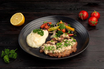 fried steak and mashed potatoes with fresh vegetables salad on a round plate