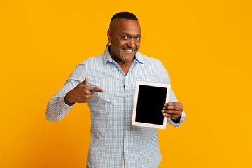 Middle aged black man pointing finger at blank digital tablet screen