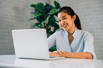 Happy friendly Asian woman using a laptop and talking, making video call conference, online job interview at home. Millennial female internet teacher tutor and vlogger working from home on the job.