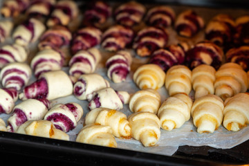 Grandmother making handmade tasty butter rolling cookies with fruit and berry jam on oven tray before baking at kitchen indoor. Rolled spin homemade healthy pastry preparing