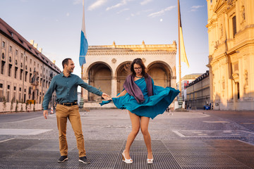 Beautiful couple had a date in the old town, girl trying to stop her flying dress by one hand and...