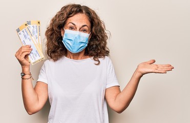 Middle age brunette woman wearing coronavirus protection mask holding canceled boarding pass...