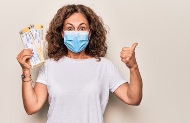 Middle age brunette woman wearing coronavirus protection mask holding canceled boarding pass...