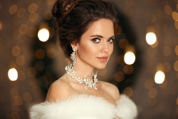 Elegant woman in white fur. Winter fashion portrait of Beautiful bride young with diamond earrings...