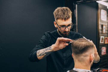 Rear view shot of handsome hairdresser cutting hair of male client. Hairstylist serving client at barber shop