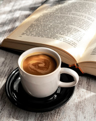 Taza de café con plato negro y libros