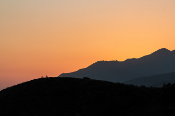 Obraz premium sunset mountain view, two silhouettes on a mountain