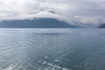 A mystical fjord in Norway with mountains and fog hanging over the water in a beautiful monochrome blue color. selective focus