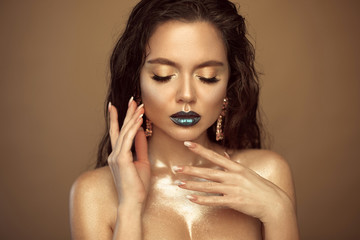 High Fashion girl model metallic golden woman with glowing make-up glitter lips, shiny face and...