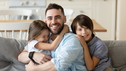 Happy small brother sister cuddling smiling dad, looking at camera. Head shot portrait joyful little children missed daddy, celebrating Father s Day, spending free weekend leisure time together.