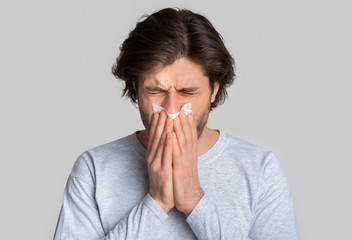 Portrait of sick man, sneezing with napkin