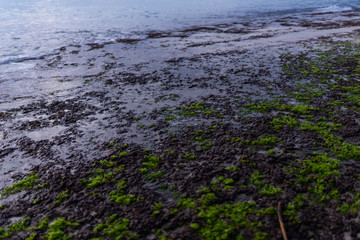 Beautiful deserted beach on the island of Bali at sunset. Rocks and nature. Plants and houses on the coast. Tropical paradise. Stones and white sand on the ocean