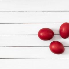 Naklejka na ściany i meble Natural easter concept. Red colored eggs on white wooden background. Flat lay, top view, copy space