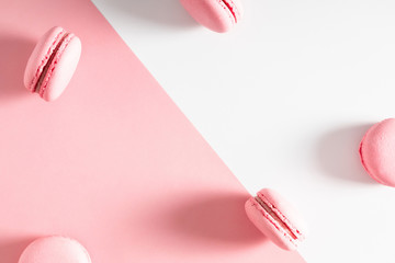 Pink macaroons on pink and white background. Almond cookies as  background. Sweet french macaroon. Flat lay, top view, copy space. Flat lay, top view, copy space