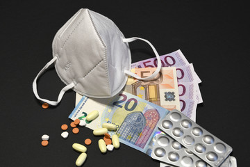 The cost of COVID-19 pandemic concept with ffp2 or KN95 prevention mask, medicines and euro currency on black background.