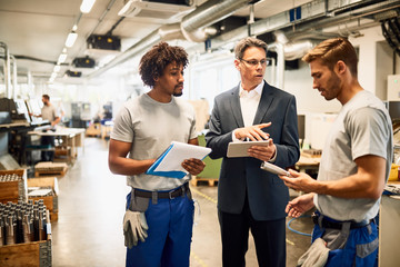 Quality control inspector and young workers communicating at streel factory.