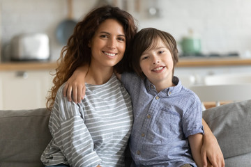 Happy little child boy embracing elder sister, portrait. Head shot young woman nanny babysitter...