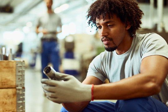 Young Black Worker Examining Stainless Steel Products In Distribution Warehouse.