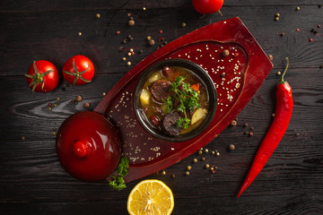 vegetable stew with potatoes and meat in a pot on a dark wooden background