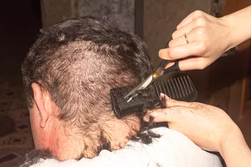 Selbstklebende Fototapeten Friseursalon Men's haircut with scissors, poor hairdresser, improper haircut of black hair. Bad day at the hairdresser, inability, problem  © NataliaSavilova