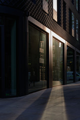 Low yellow sunlight reflecting off building window onto pavement towards viewer