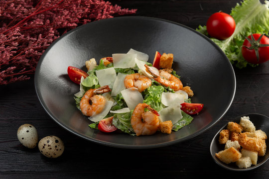 caesar salad with shrimp on a dark wooden background